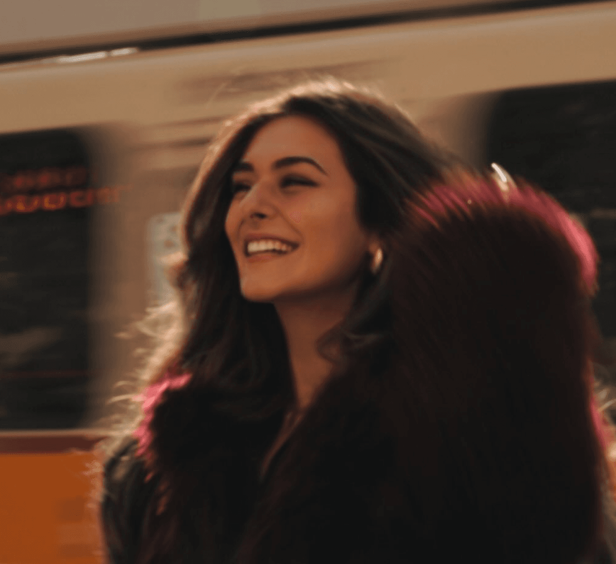 Portrait of the founder smiling in a deep red coat, hair catching the light
