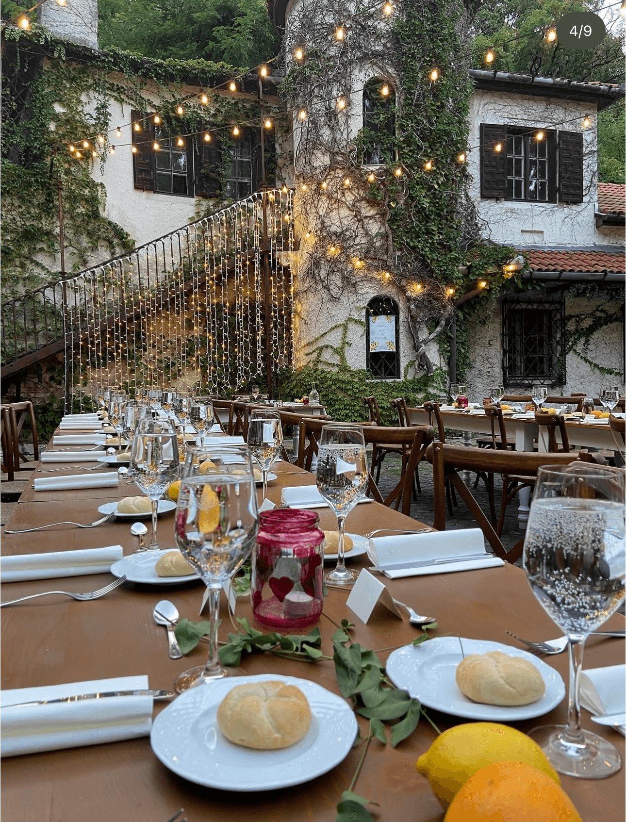 Ivy-covered courtyard venue strung with festoon lights, long tables set for a wedding dinner