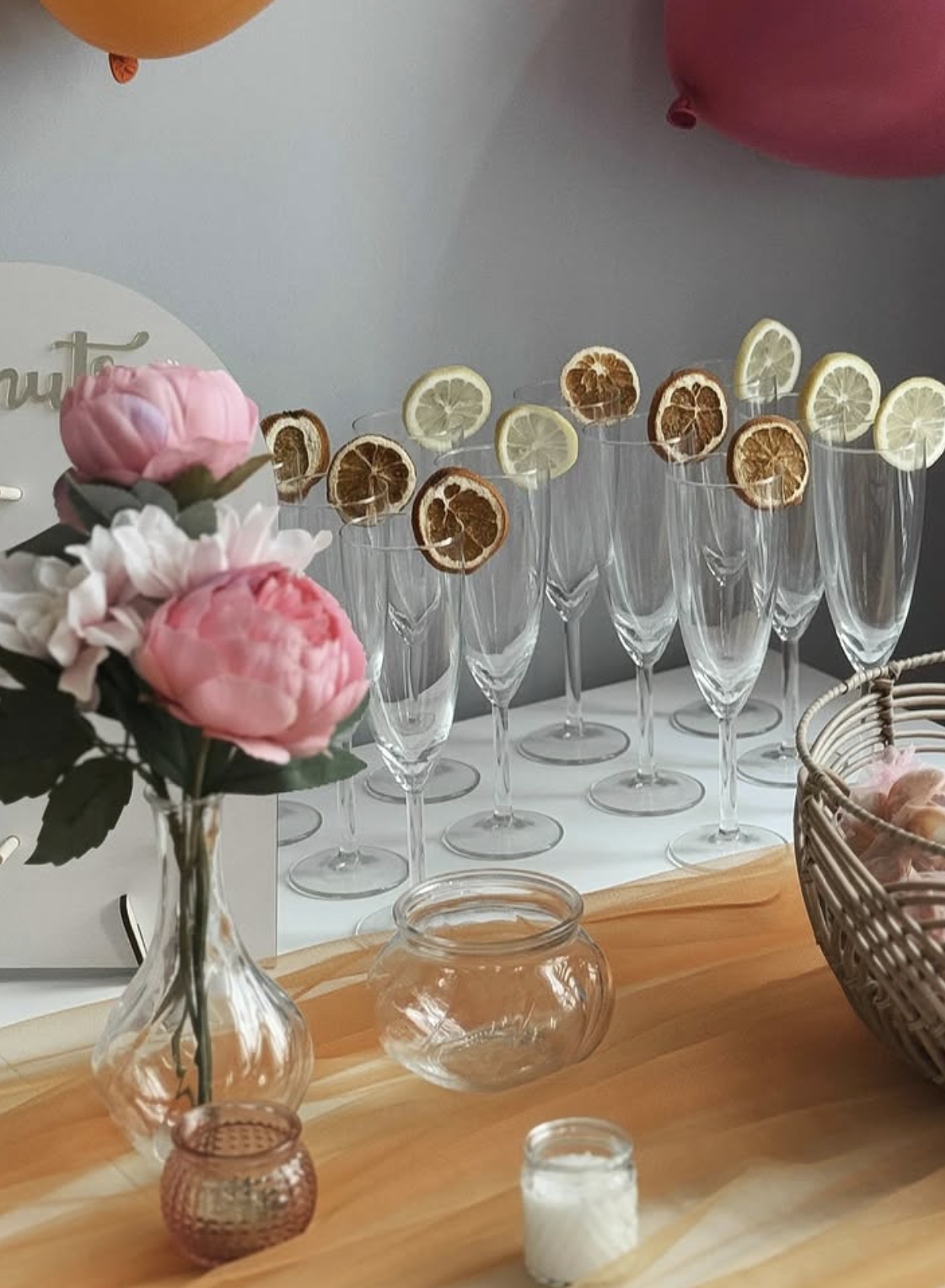 Champagne flutes garnished with dried citrus beside peonies and woven baskets at a bridal party